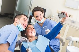 patient in dental chair taking a selfie with her dentist that will be shared on social media and used on social media for dentists  