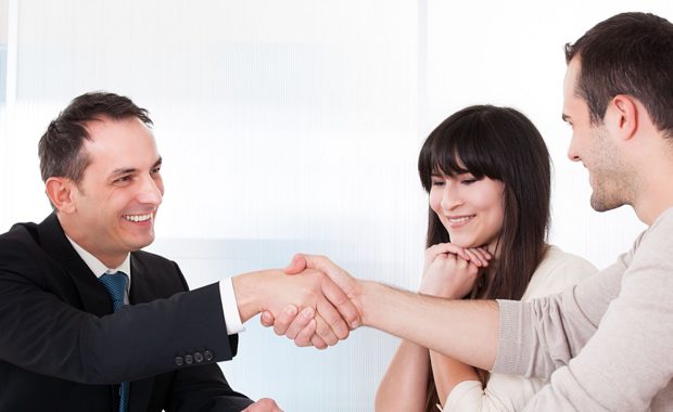 an insurance agent shaking hands with a couple who found his agency through a good insurance marketing campaign that has been running for several months