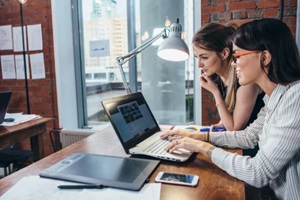 two women working on new website design choosing pictures using the laptop surfing the internet
