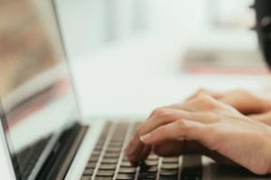 women typing on laptop